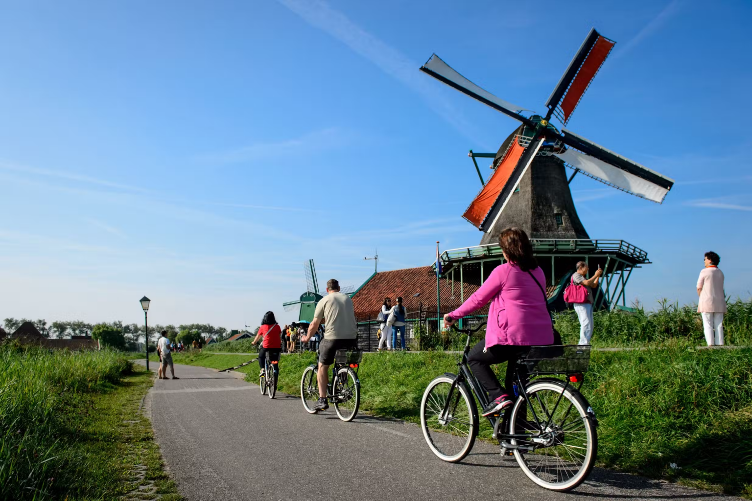 Cyclists on the dike past the windmills